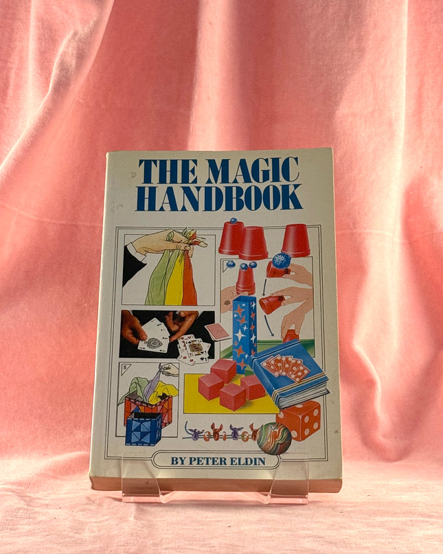 Book titled 'The Magic Handbook' by Peter Eldin on a pink background