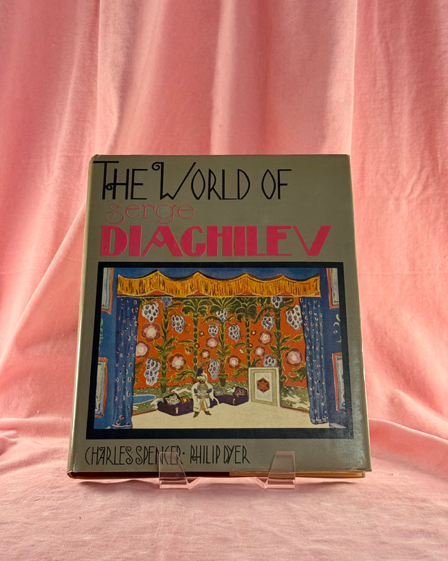 Book titled 'The World of Diaghilev' on a pink fabric background