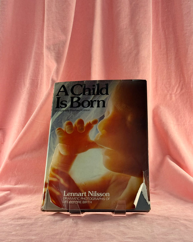Book titled 'A Child Is Born' by Lennart Nilsson on a pink fabric background