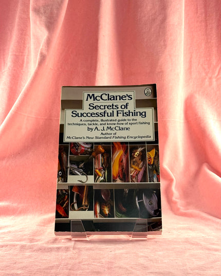 Book titled 'McClane's Secrets of Successful Fishing' on a pink fabric background