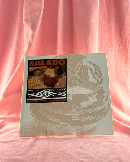 Album cover with 'SALADO' and a graphic design on a pink fabric background