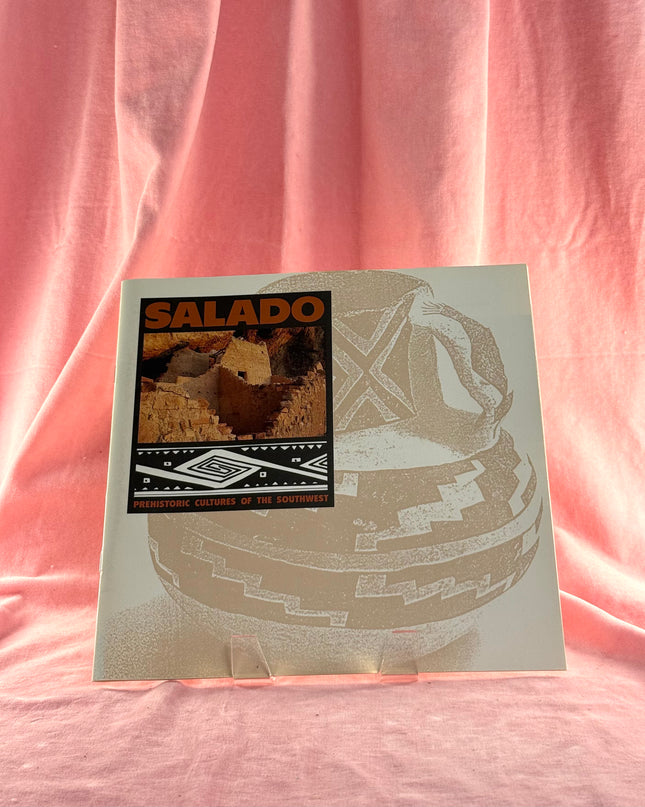 Album cover with 'SALADO' and a graphic design on a pink fabric background