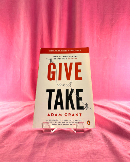 Book titled 'Give and Take' by Adam Grant on a pink background