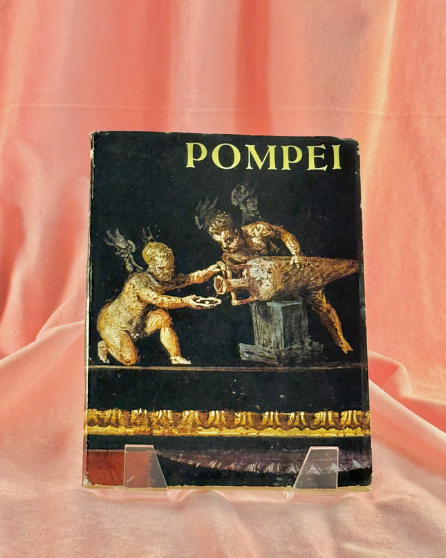 Book titled 'Pompei' with classical design on a pink fabric background