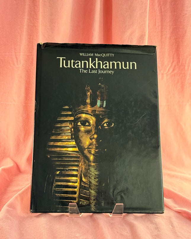 Book titled 'Tutankhamun: The Last Journey' by William MacGaffey on a pink fabric background