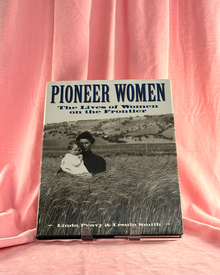 Book titled 'Pioneer Women: The Lives of Women on the Frontier' on a pink fabric background