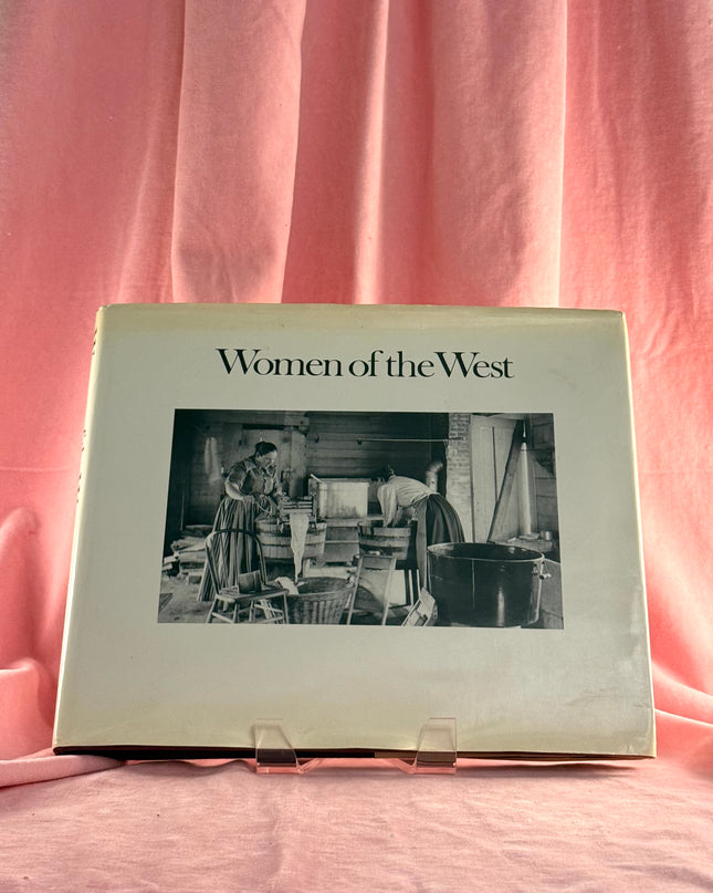 Book titled 'Women of the West' on a pink fabric background