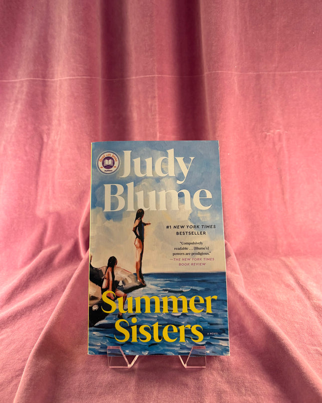 Book titled 'Summer Sisters' by Judy Blume on a pink background