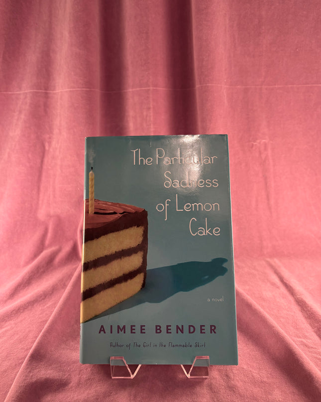 Book titled 'The Particular Sadness of Lemon Cake' by Aimee Bender on a pink background
