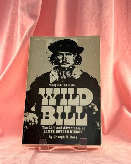 Book titled 'The Life and Adventures of James Butler Hickok' with a cover featuring a silhouette on a pink fabric background.