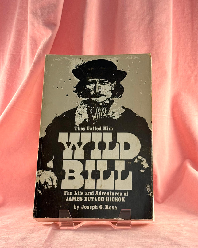 Book titled 'The Life and Adventures of James Butler Hickok' with a cover featuring a silhouette on a pink fabric background.