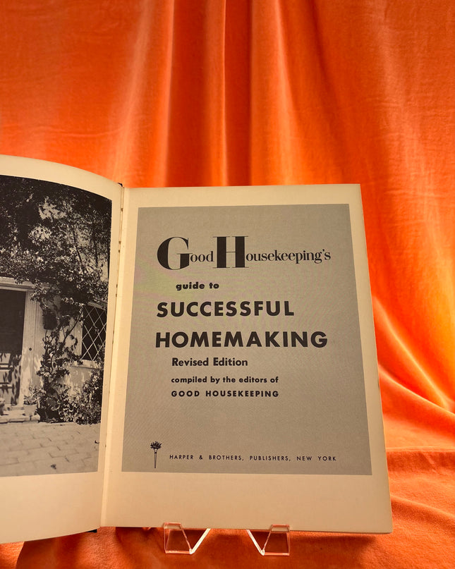 Open book titled 'Good Housekeeping's Guide to Successful Homemaking' on an orange fabric background
