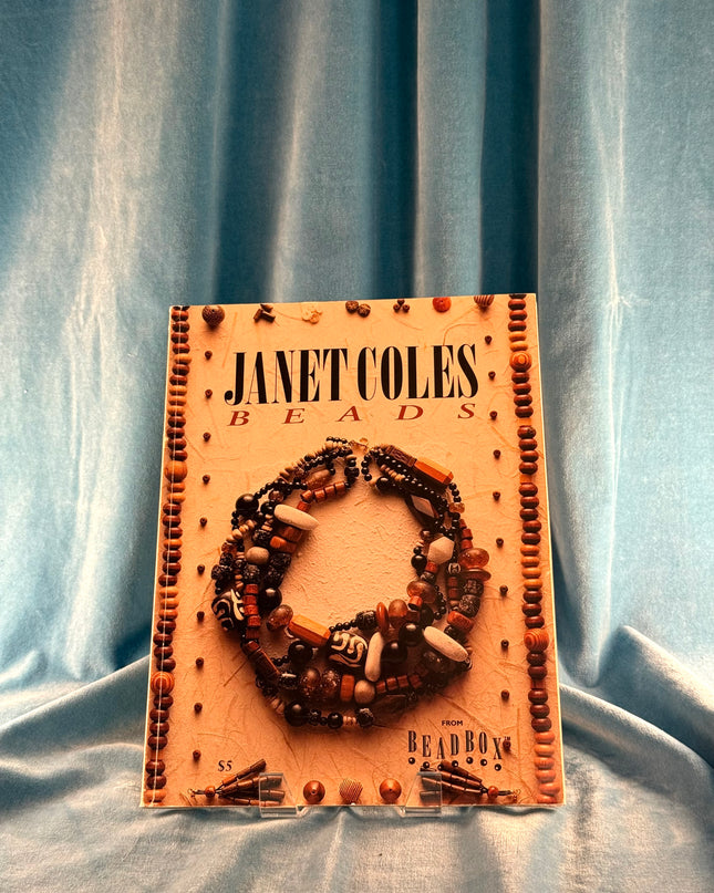 Janet Coles Beads product packaging with a bracelet on a blue fabric background