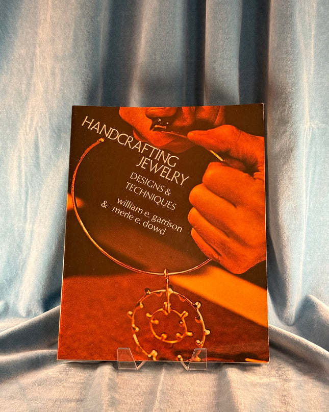 Book titled 'Handcrafting Jewelry: Designs & Techniques' on a gray fabric background