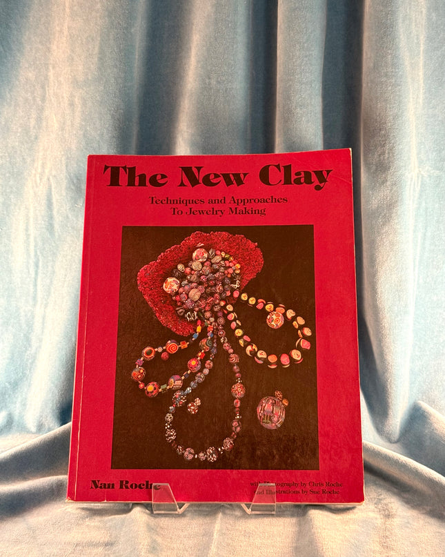 Book titled 'The New Clay' on a textured fabric background