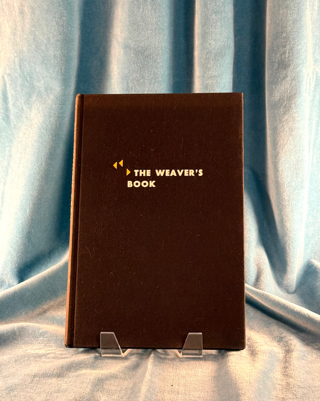 Brown book titled 'The Weaver's Book' on a light blue fabric background
