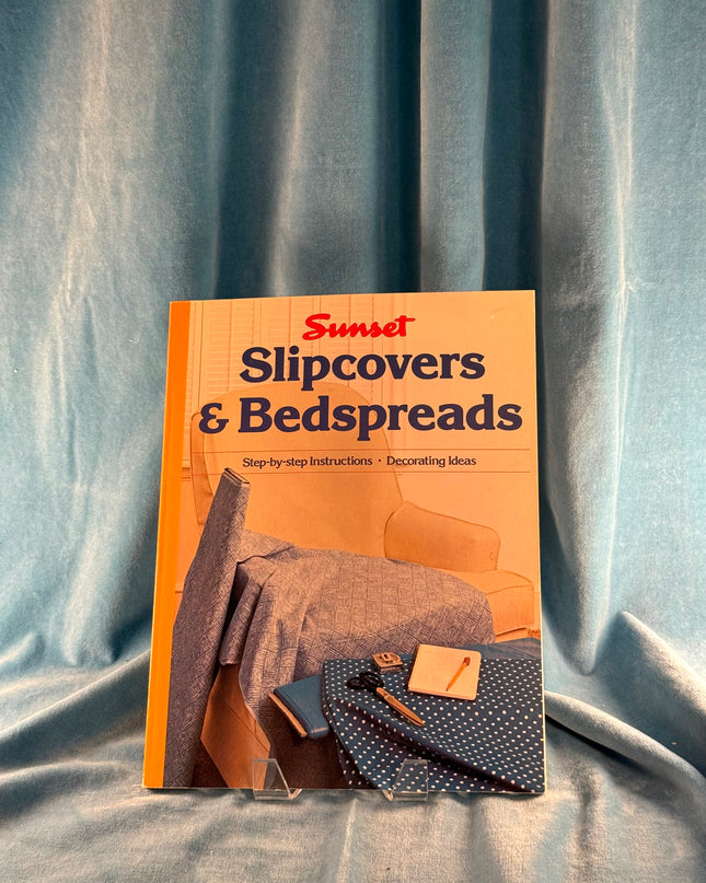 Book titled 'Sunset Slipcovers & Bedspreads' on a textured fabric background