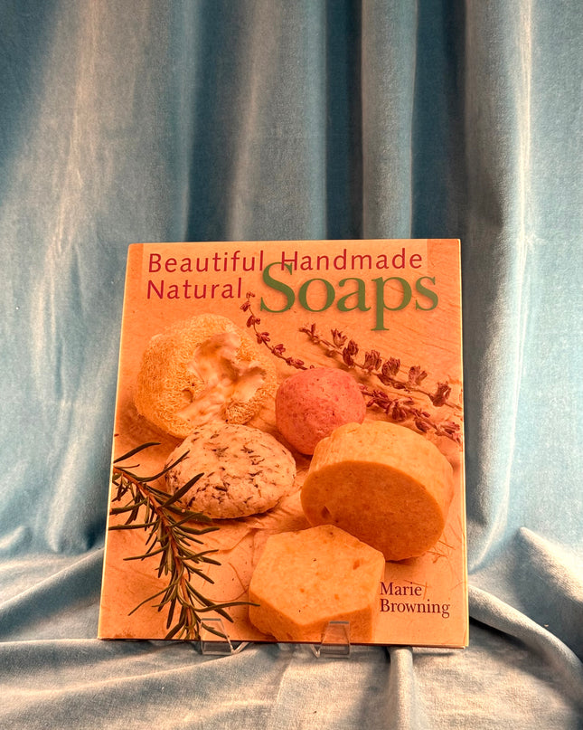 Book titled 'Beautiful Handmade Natural Soaps' by Marie Browning on a textured fabric background
