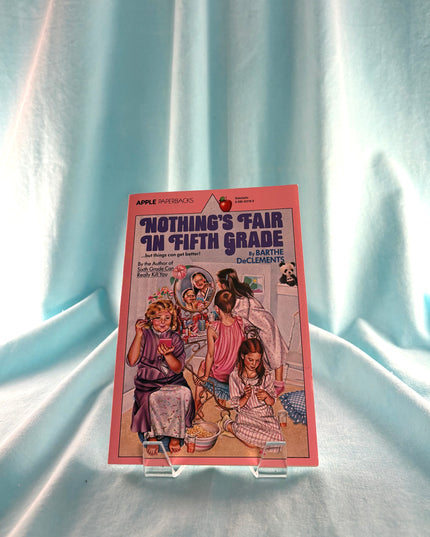 Book titled 'Nothing's Fair in Fifth Grade' by Barthe DeClements on a light blue fabric background