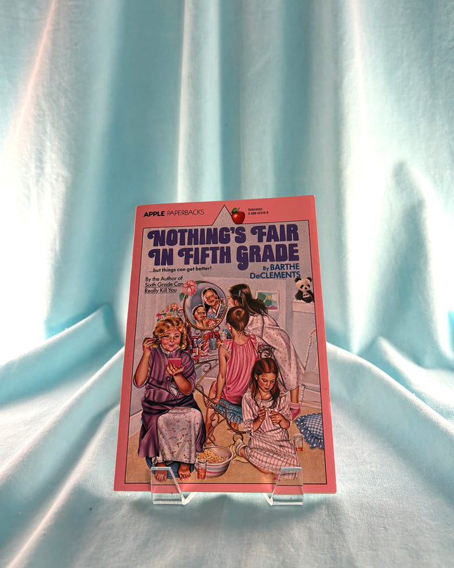 Book titled 'Nothing's Fair in Fifth Grade' by Barthe DeClements on a light blue fabric background