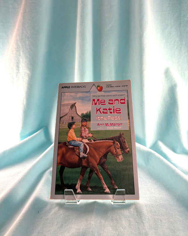 Book titled 'Me and Katie' on a stand with a white curtain background