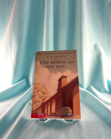 Book titled 'The Horse and His Boy' by C.S. Lewis on a stand against a light blue curtain background