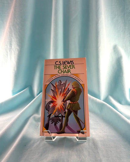 Book cover of 'The Silver Chair' by C.S. Lewis on a stand against a light blue curtain background
