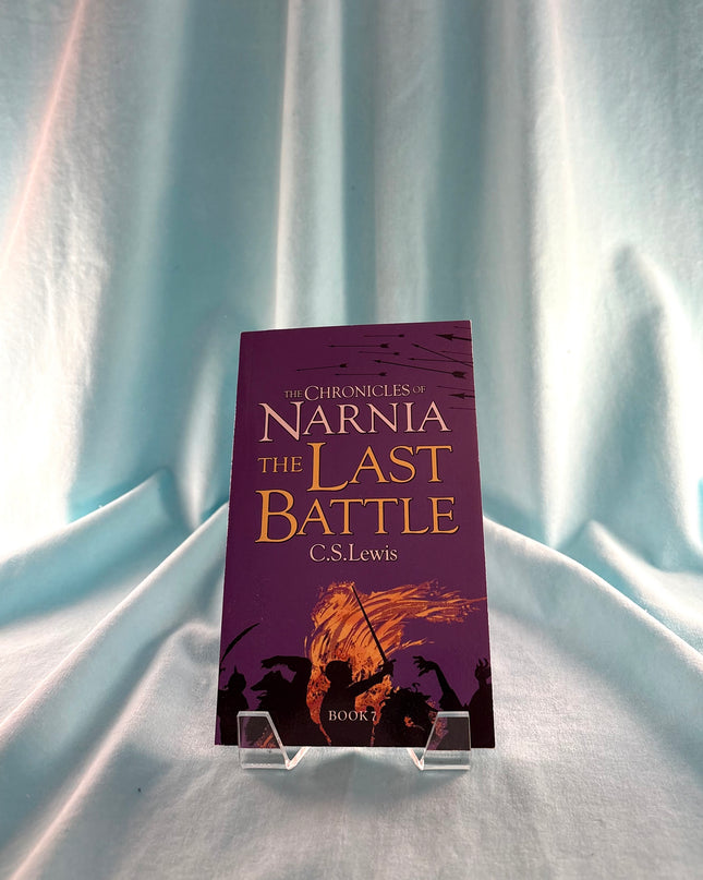 Book titled 'The Last Battle' from 'The Chronicles of Narnia' series on a stand against a light curtain background