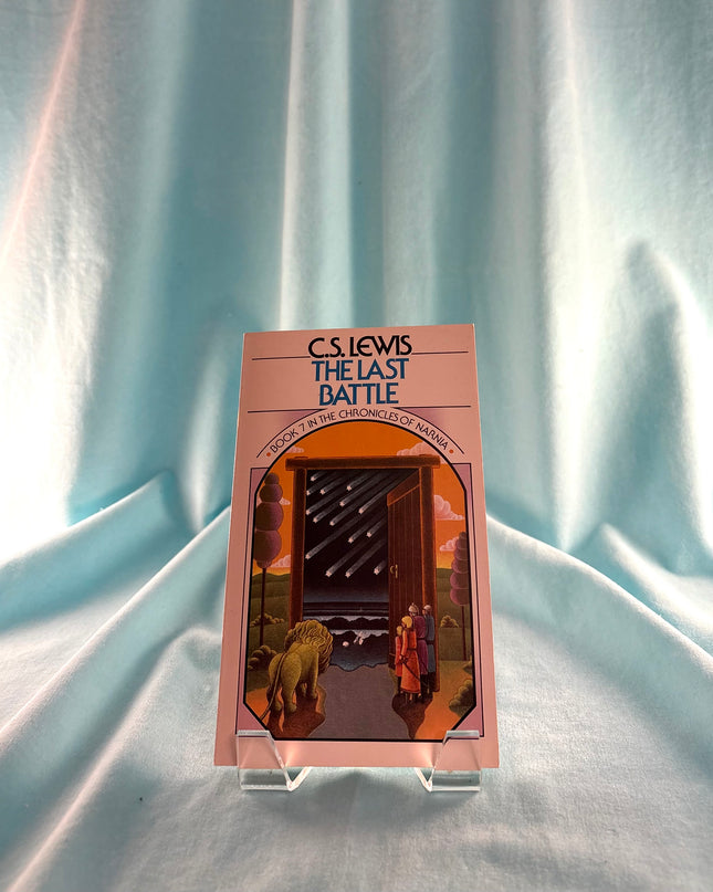 Book cover of 'The Last Battle' by C.S. Lewis on a clear stand against a light blue fabric background