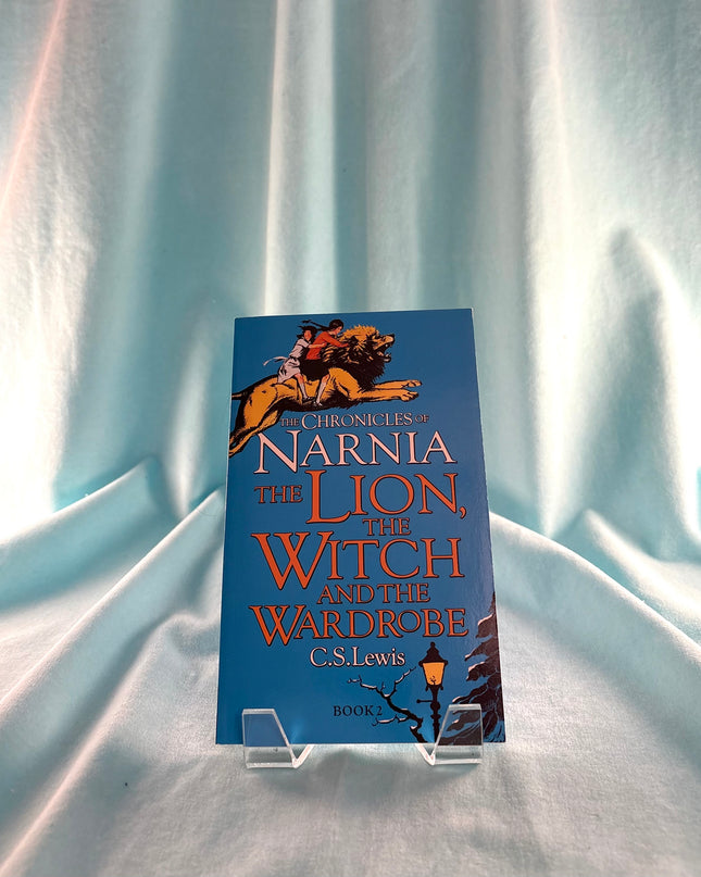 Book titled 'The Chronicles of Narnia: The Lion, the Witch and the Wardrobe' by C.S. Lewis on a light blue fabric background.