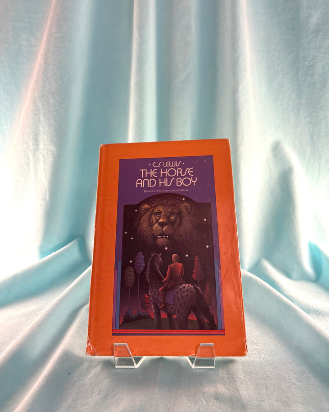 Book titled 'The Horse and His Boy' on a stand with a light blue curtain background