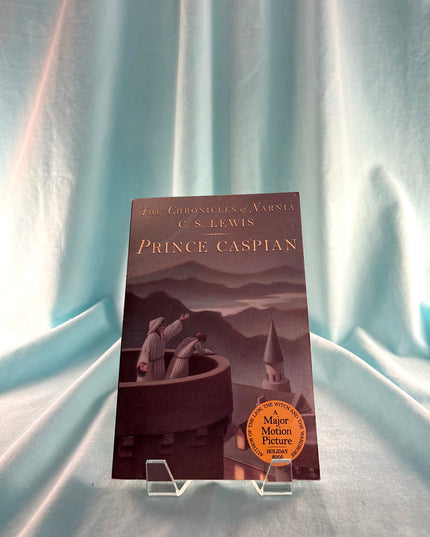 Book titled 'Prince Caspian' by C.S. Lewis on a stand with a soft blue curtain background