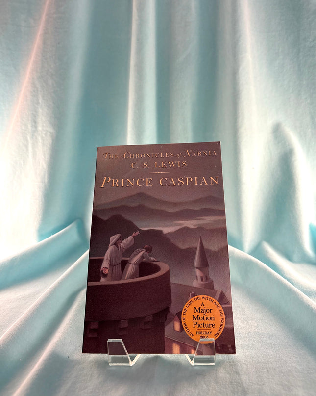 Book titled 'Prince Caspian' by C.S. Lewis on a stand with a soft blue curtain background