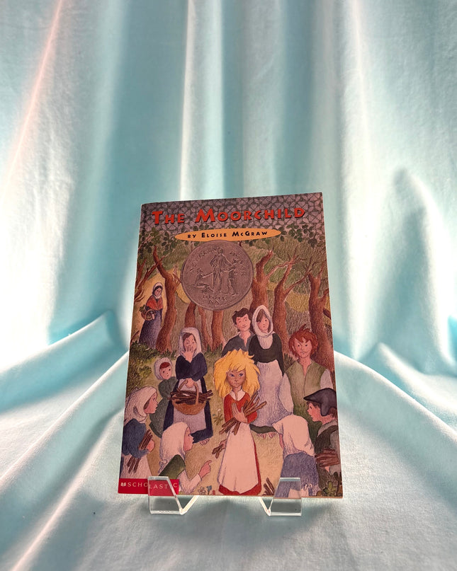 Book titled 'The Moorchild' on a stand against a light blue curtain background