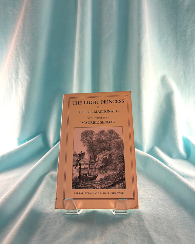 Book titled 'The Light Princess' by George MacDonald with illustrations by Maurice Sendak, displayed on a stand against a light blue fabric background.