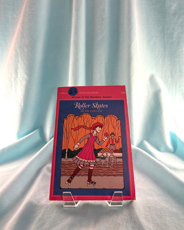 Book titled 'Roller Skates' on a stand against a light blue curtain background
