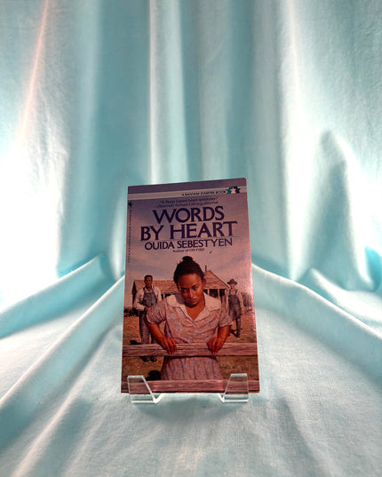 Book titled 'Words By Heart' by Ouida Sebestyen on a light blue fabric background