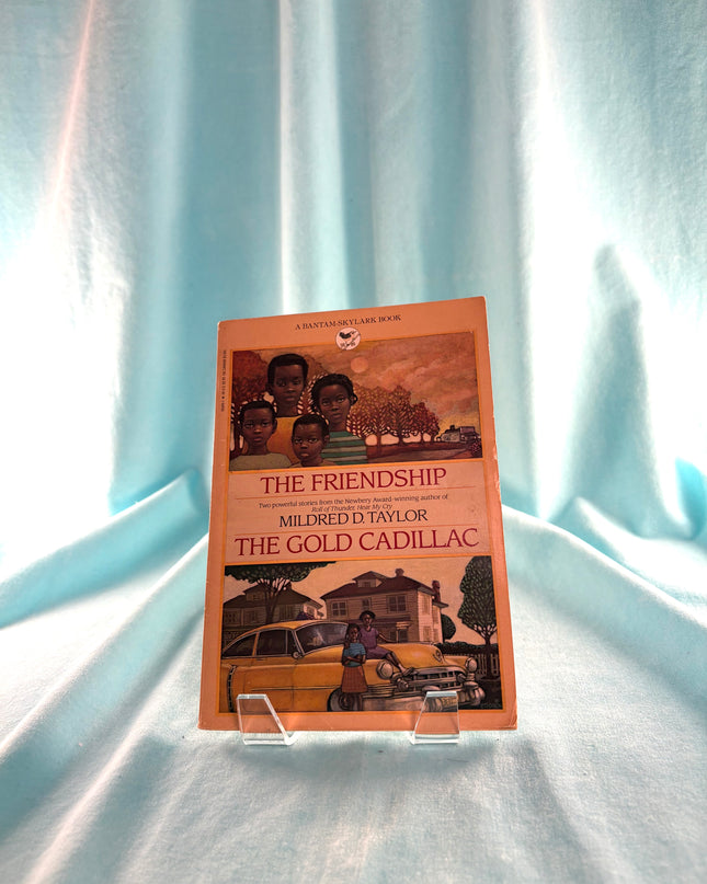 Book titled 'The Gold Cadillac' by Mildred D. Taylor on a light blue fabric background