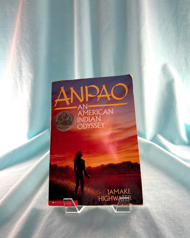 Book titled 'Anpao: An American Indian Odyssey' on a stand with a light blue curtain background