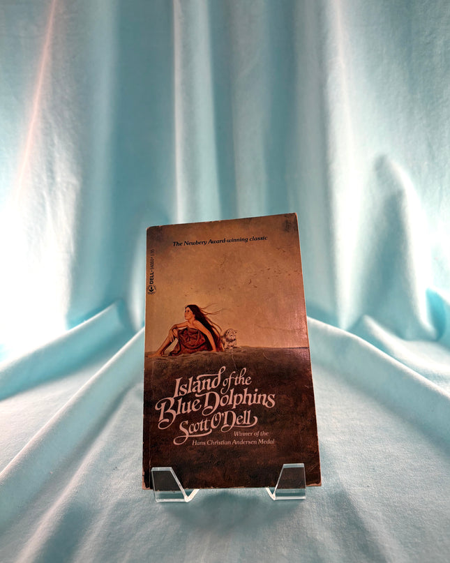 Book titled 'Island of the Blue Dolphins' on a light blue fabric background