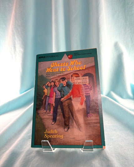 Book titled 'Ghosts Who Went to School' by Judith Spearing on a stand against a light curtain background