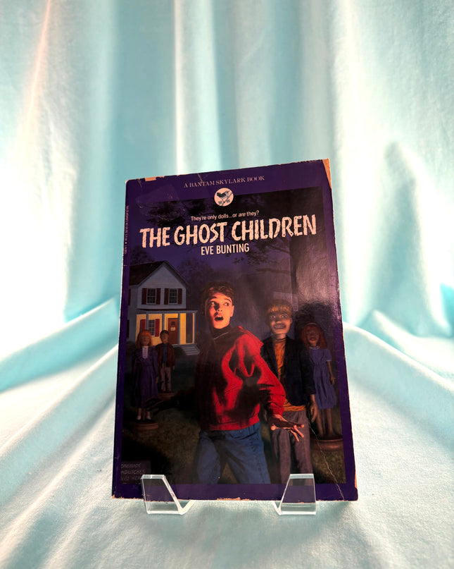 Book titled 'The Ghost Children' by Eve Bunting on a stand against a light curtain background