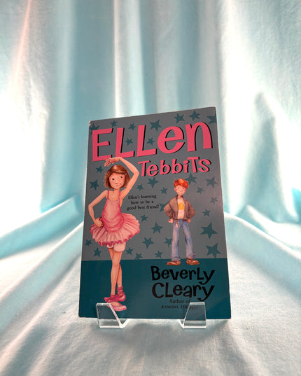 Book titled 'Ellen Tubb's' by Beverly Cleary on a stand with a light blue curtain background