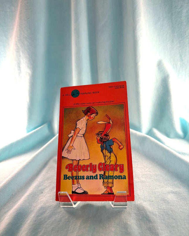 Book titled 'Beezus and Ramona' by Beverly Cleary on a stand against a light curtain background