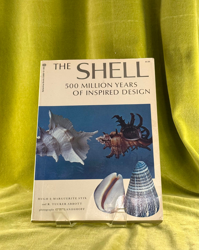 Book titled 'The Shell: 500 Million Years of Inspired Design' on a green fabric background