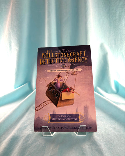Book titled 'The Wollstonecraft Detective Agency' on a light blue fabric background