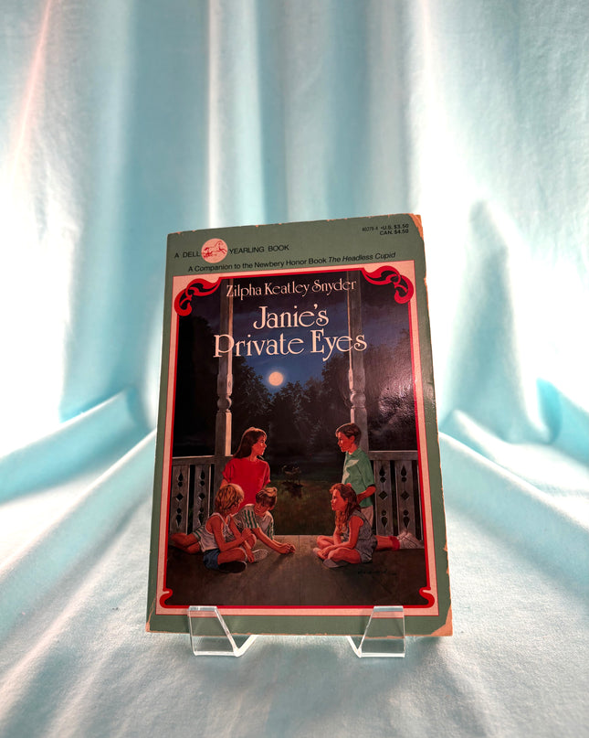 Book titled 'Janie's Private Eyes' on a light blue curtain background