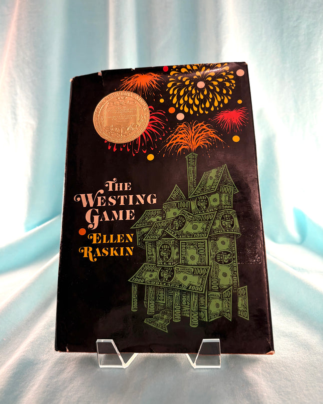 Book titled 'The Westing Game' by Ellen Raskin with a decorative cover on a light fabric background.