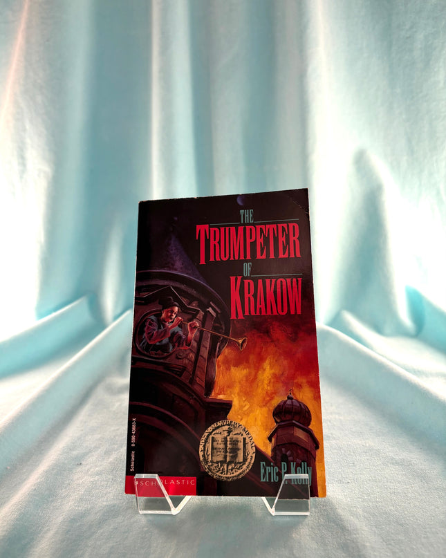 Book titled 'The Trumpeter of Krakow' on a stand against a light curtain background