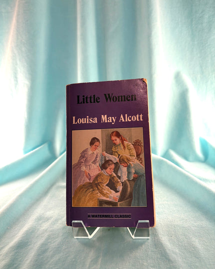 Book titled 'Little Women' by Louisa May Alcott on a light blue fabric background